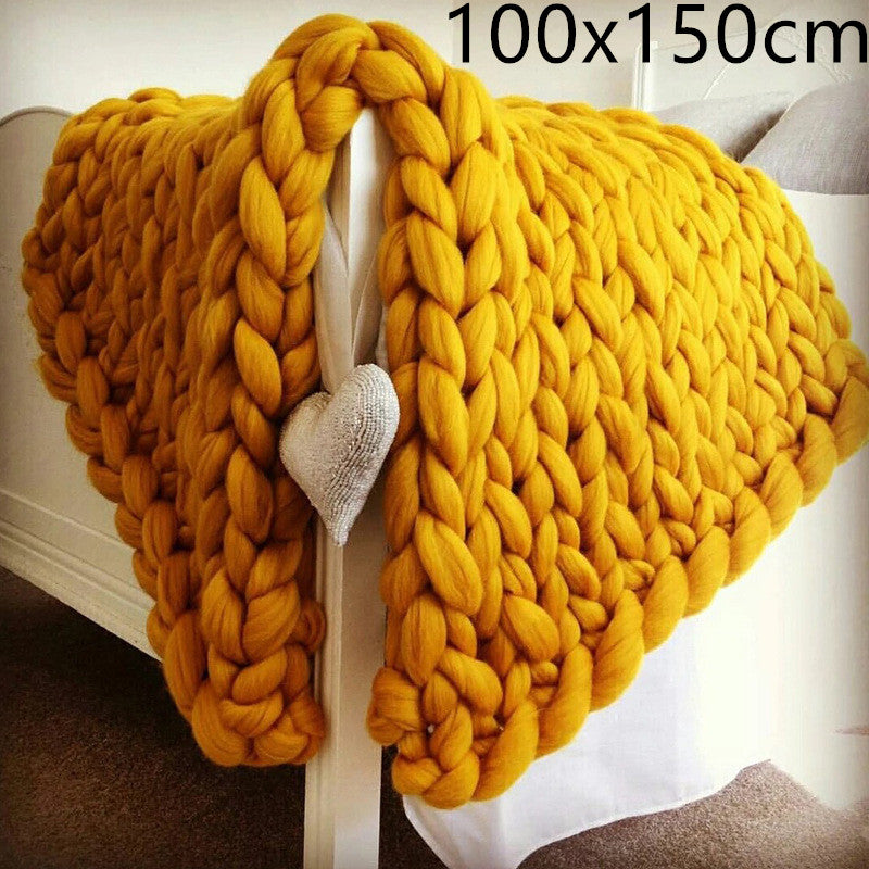 Yellow knitted blanket with a heart-shaped object draped over a white surface.